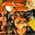 seafood boil with crabs, corn, and muscles. this image is for the blog "How to Cook a Seafood Boil."