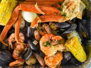 seafood boil with crabs, corn, and muscles. this image is for the blog "How to Cook a Seafood Boil." 