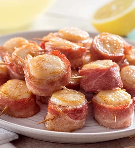 Bacon-wrapped scallops on a plate, a savory fall seafood dish.