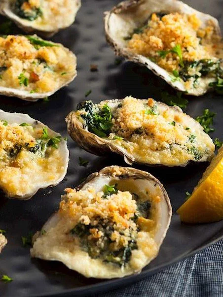 Oysters Rockefeller topped with spinach and breadcrumbs, a fall seafood appetizer.