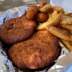 Fried crab cakes and potato wedges have been cooked using seafood seasoning to enhance their flavor